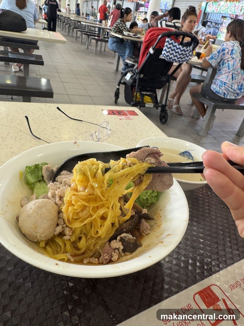 Person eating noodles at a food court