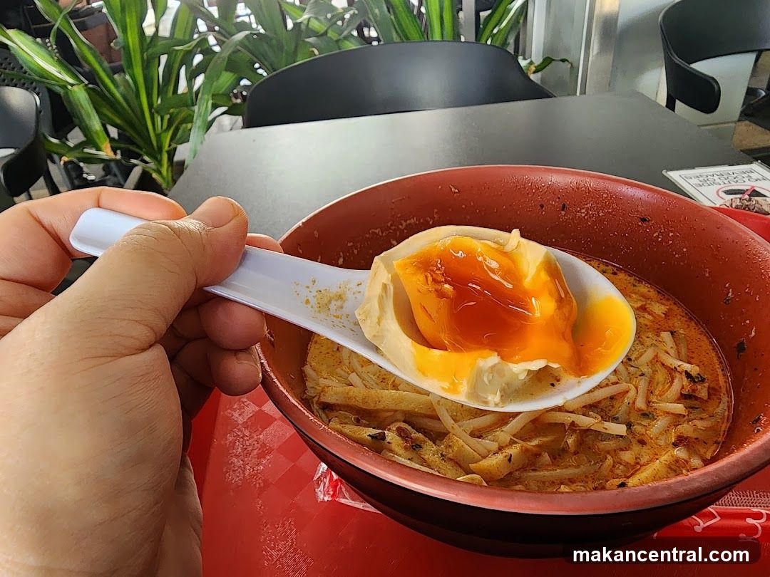 Close-up of a spoon with food over a bowl of noodles