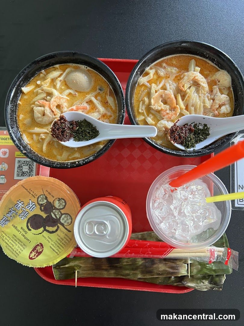 Two bowls of Laksa with toppings and a drink