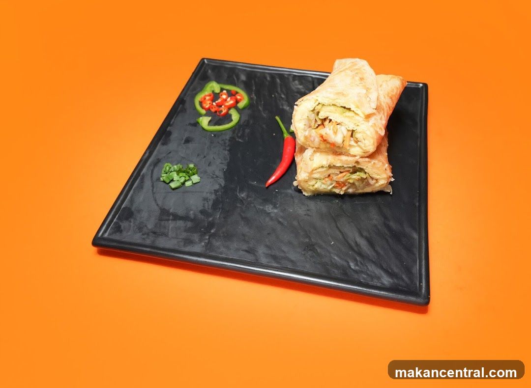 Two wraps on a black plate with garnishes