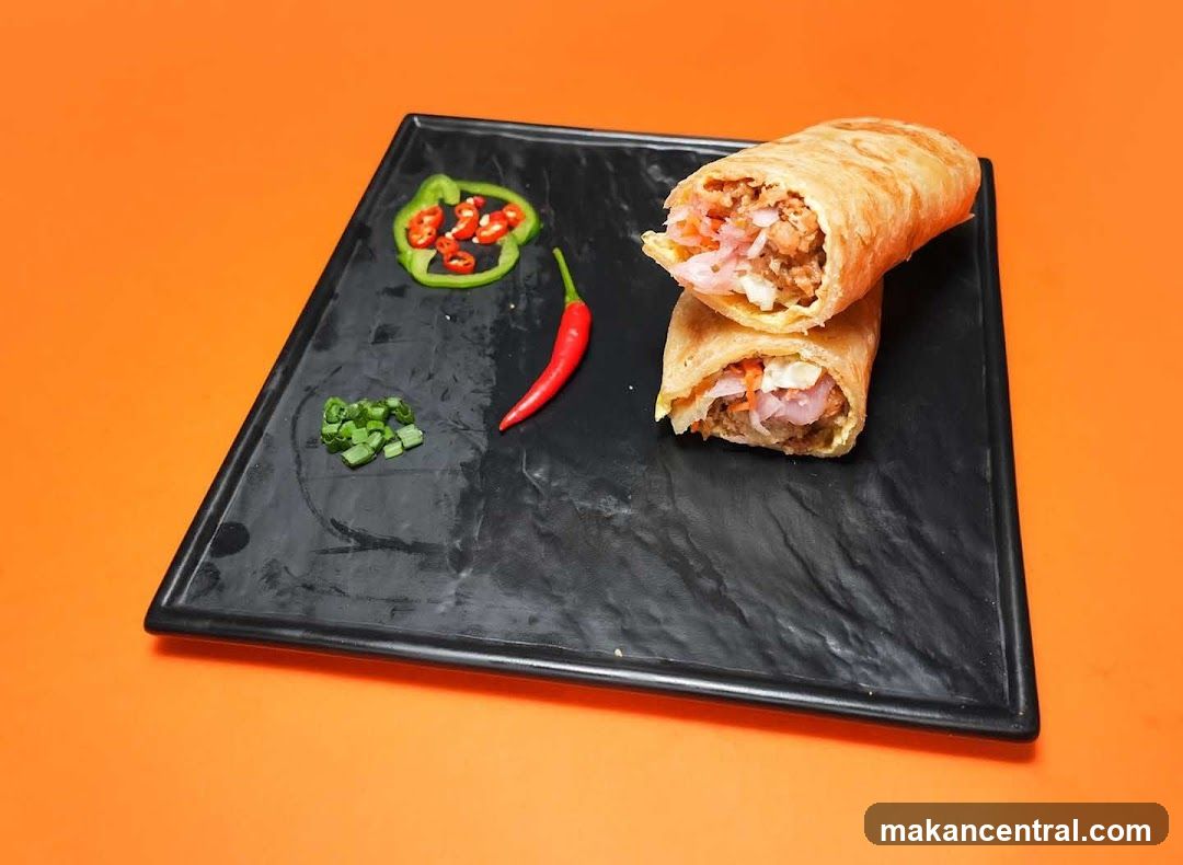 Two wraps on a black plate with garnishes