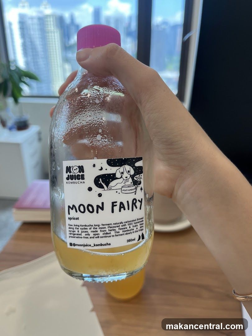 Hand holding a bottle of Moon Juice Kombucha