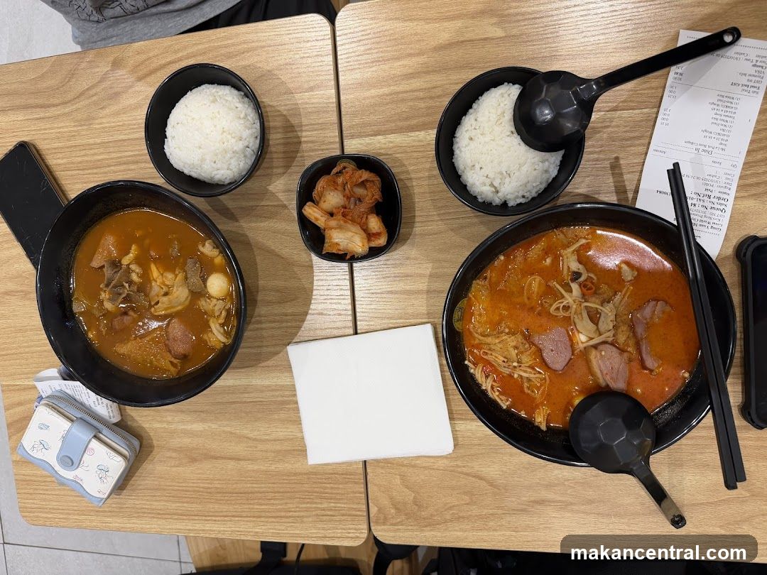 Two bowls of spicy soup with rice and kimchi