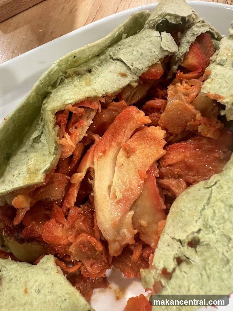 Close-up of a green wrap filled with shredded meat and sauce