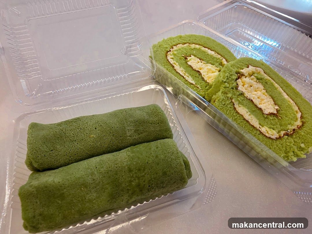 Two clear plastic containers hold green Swiss rolls. One container has two whole rolls, and the other has two slices of a Swiss roll with cream filling.