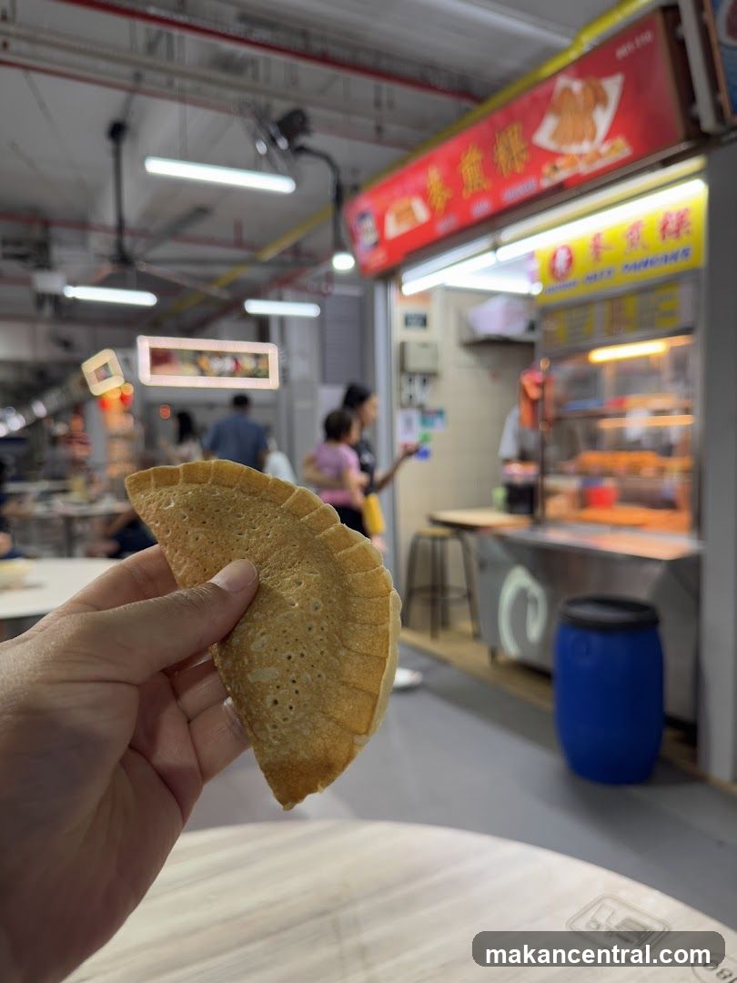 Hand holding a pancake with a food stall in the background