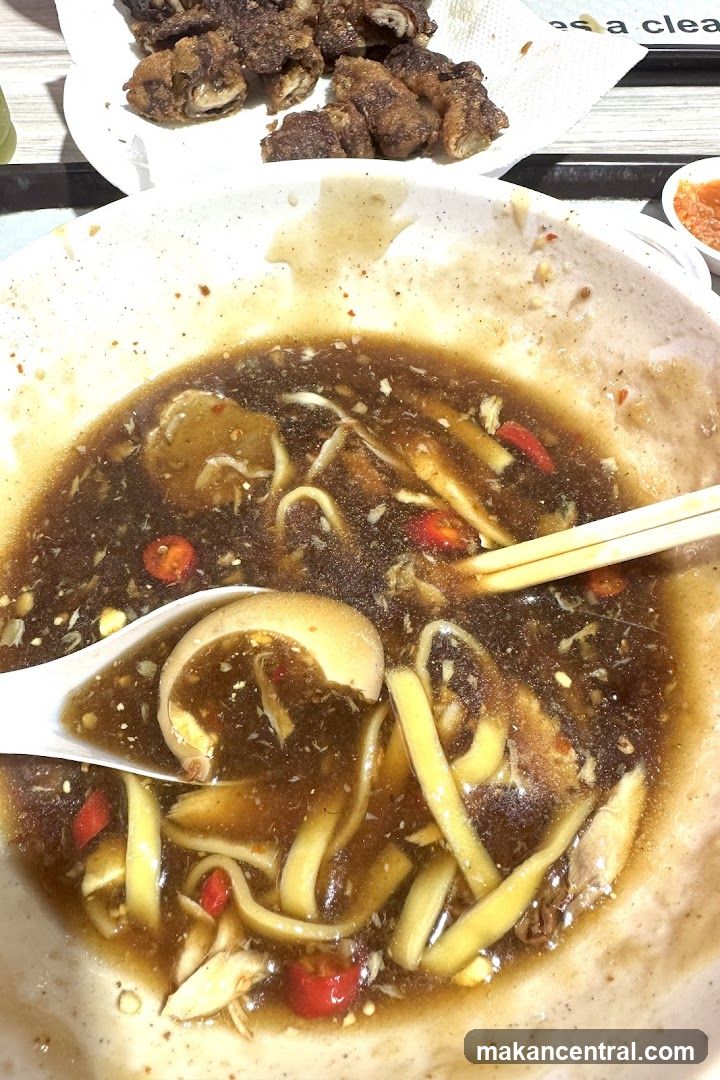 Close-up of a bowl of noodles with broth and a side of fried food
