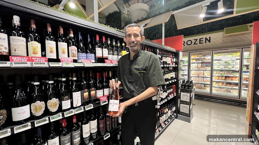 Man holding a bottle of rose wine in a supermarket aisle