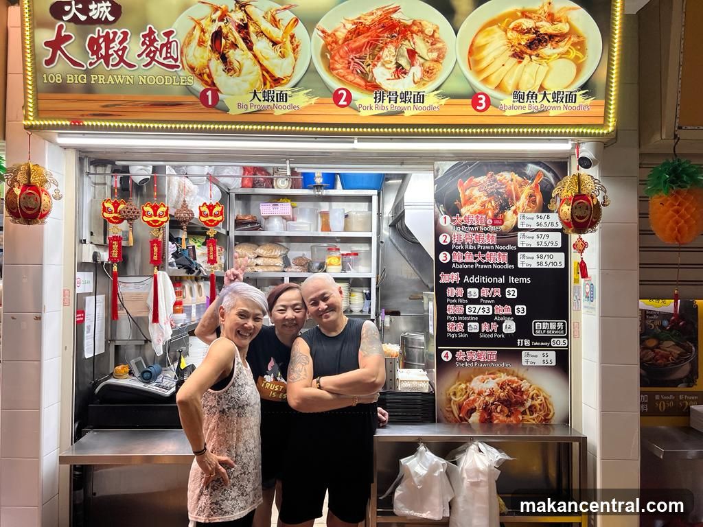 Three people posing in front of a food stall