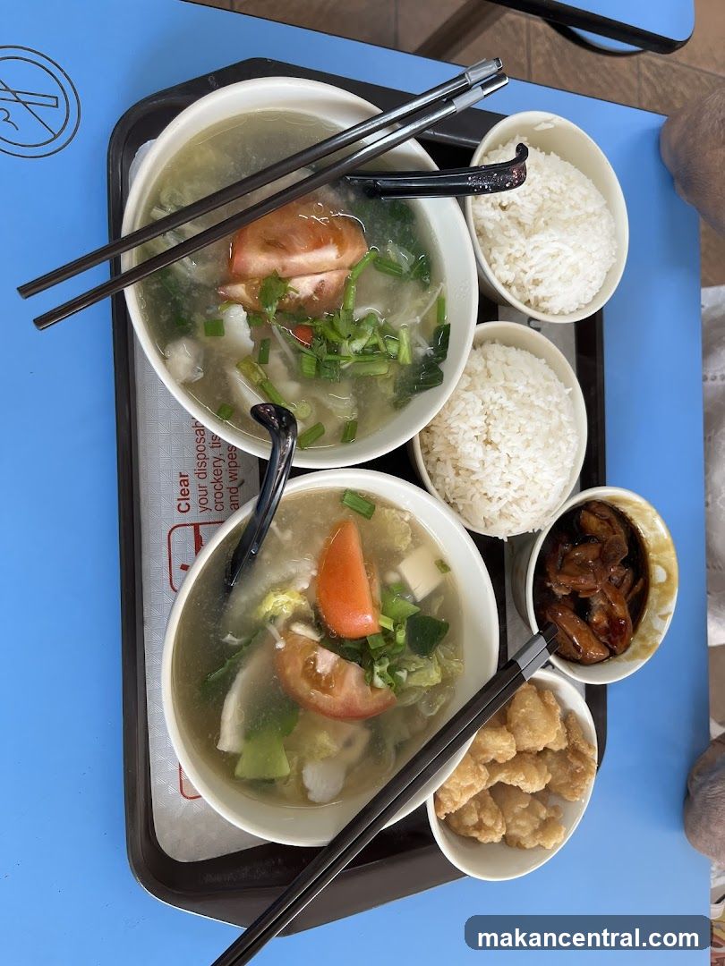 Two bowls of soup with rice and side dishes
