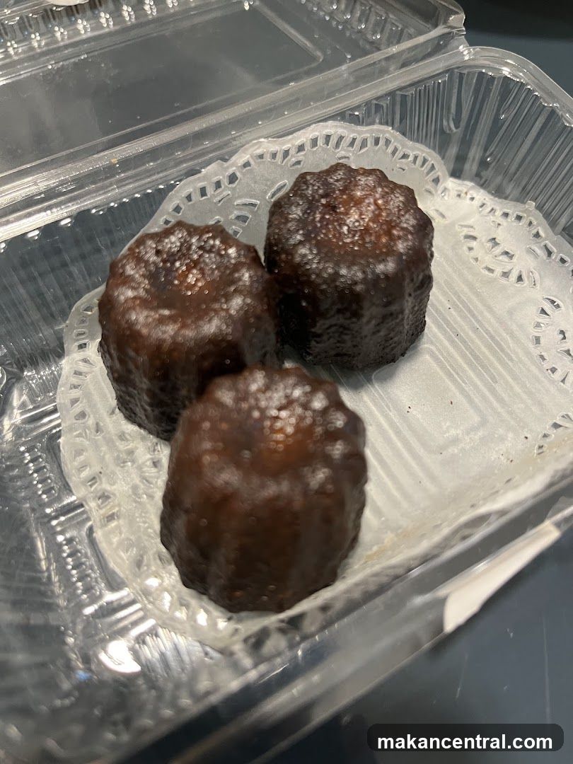 Three Canelés in a Plastic Container