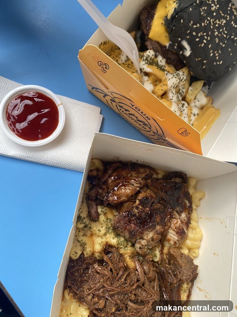 Food boxes with mac and cheese, pulled meat, chicken, and fries with a burger