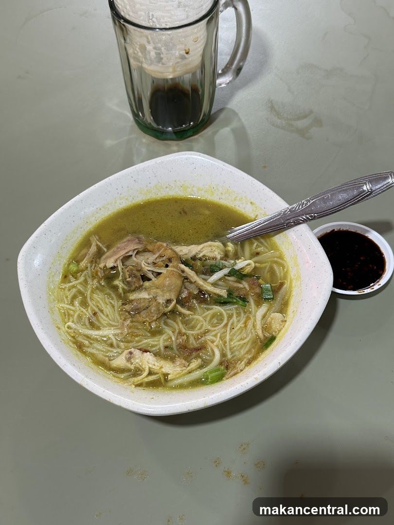 Chicken noodle soup with a side of soy sauce and a drink