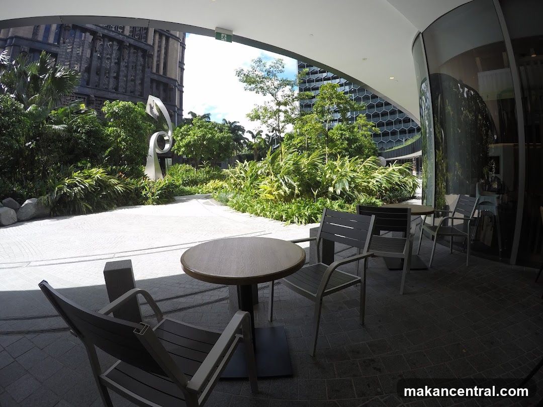 Outdoor seating area with modern sculpture and lush greenery