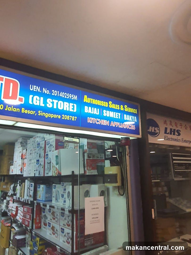 The storefront of GL Store, an authorized sales and service center for kitchen appliances. The sign indicates they sell brands like Bajaj, Sumeet, and Bakya. The store displays a variety of boxed kitchen appliances on shelves visible through the glass entrance.