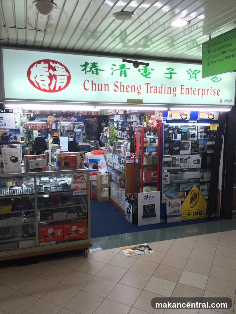 The exterior of a shop called Chun Sheng Trading Enterprise. The shop sells electronics and has various items displayed in windows and on shelves.