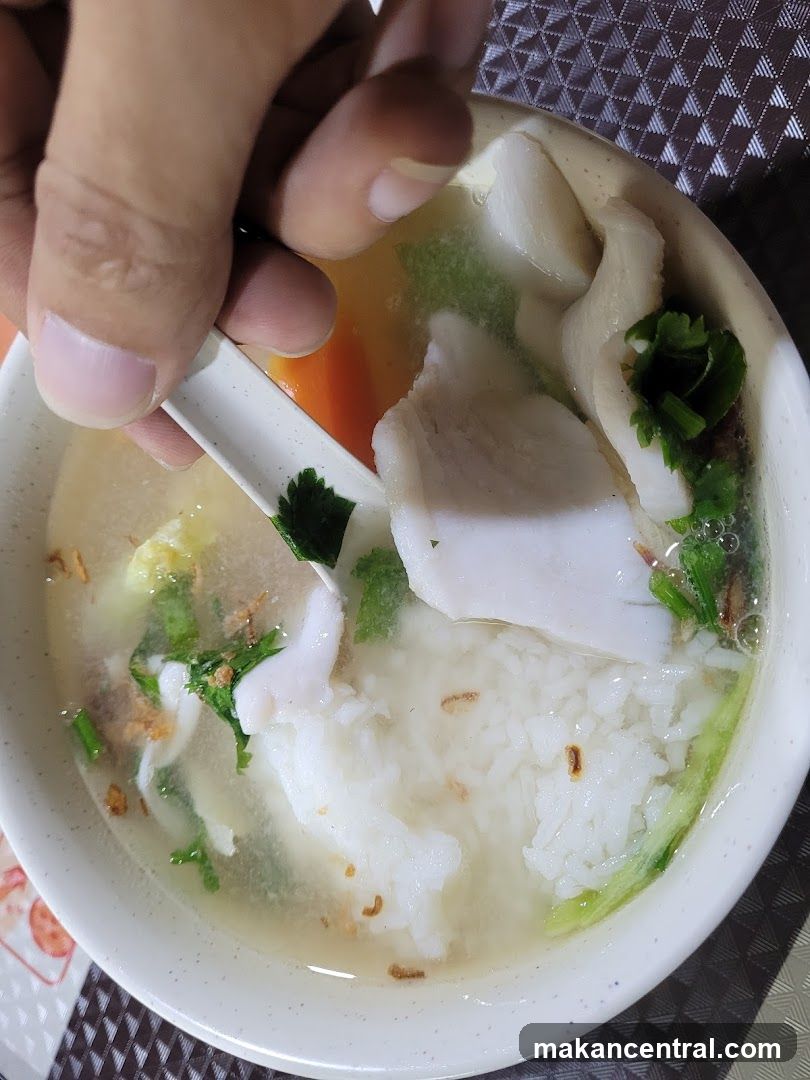 Hand holding spoon over bowl of soup