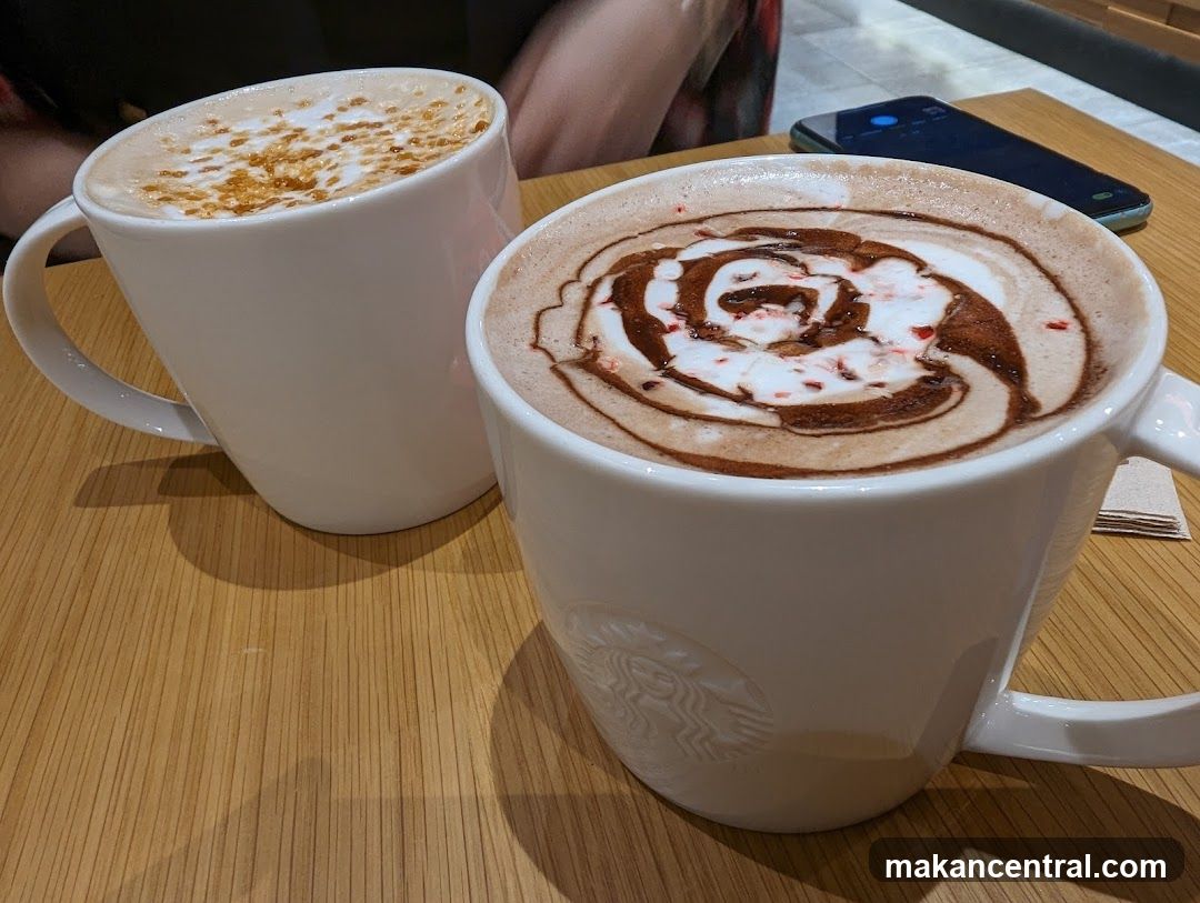 Two coffee drinks in white mugs on wooden table
