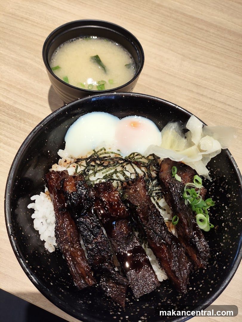 Bowl of Japanese-style rice bowl with grilled fish, soft-boiled egg, pickled vegetables, seaweed, and miso soup