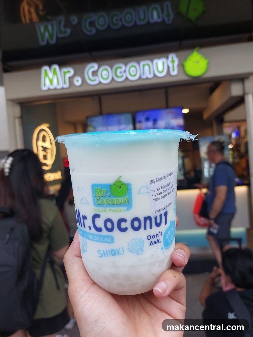 Hand holding Mr. Coconut drink in front of shop