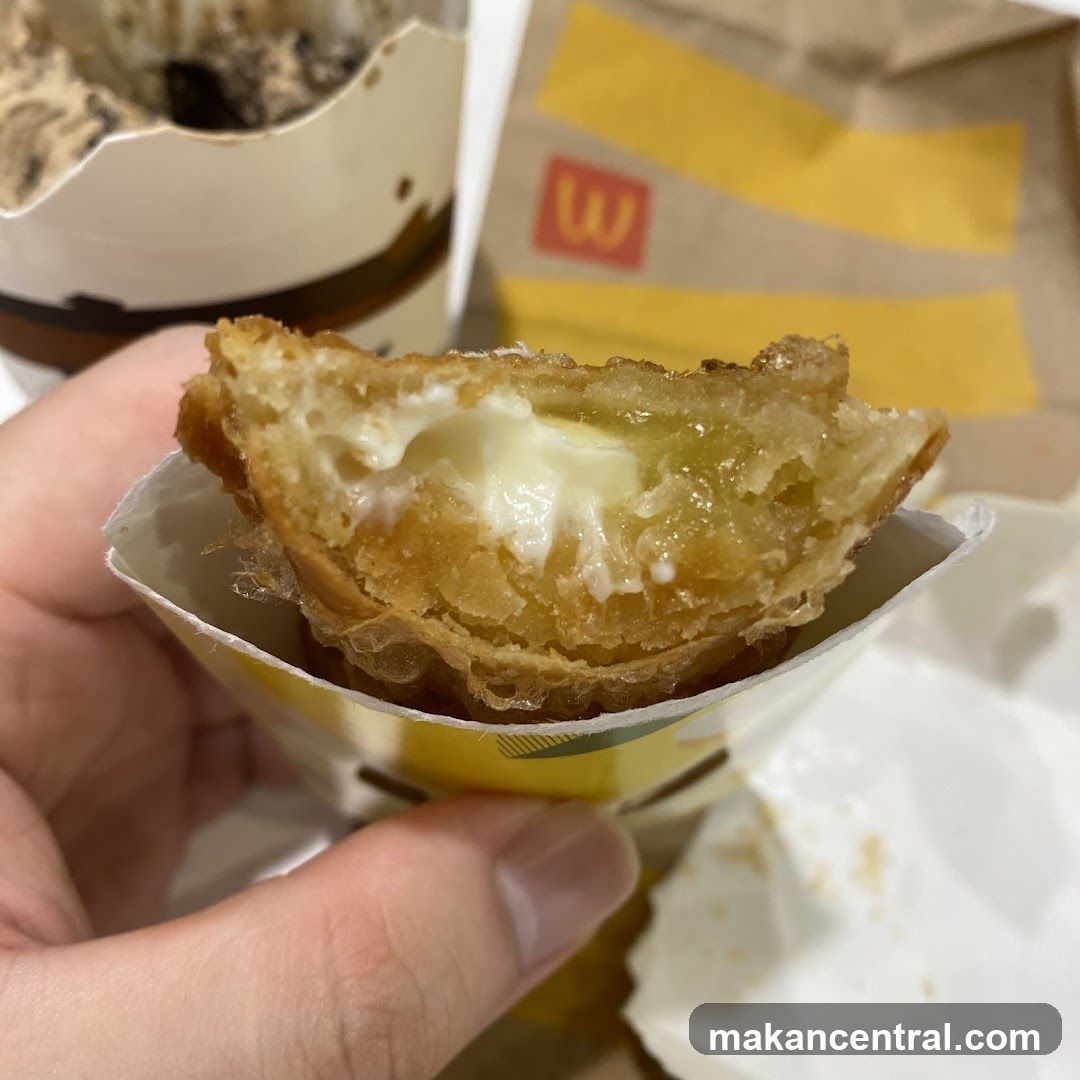 Hand holding a fried pastry with cream filling