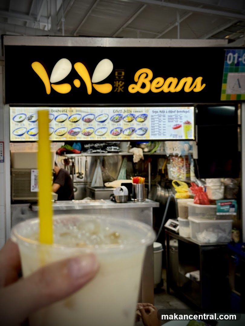 Hand holding a drink in front of a food stall