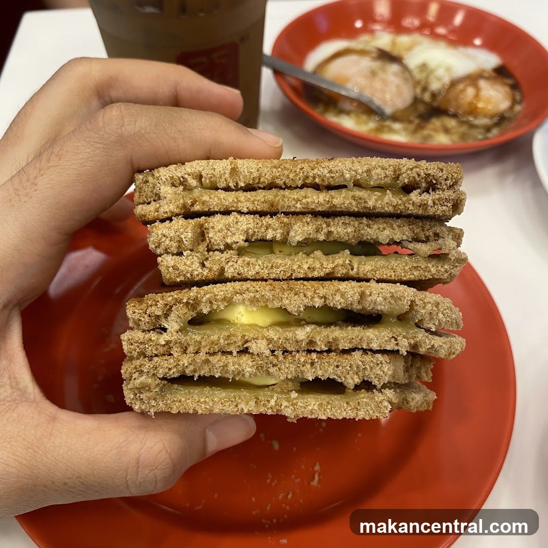 Hand holding sandwich with red plate and iced coffee in background