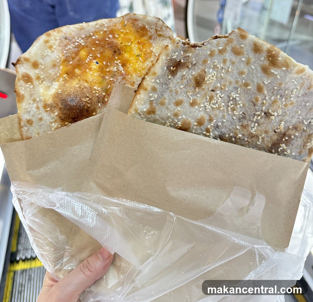 Hand holding two sesame-topped flatbreads