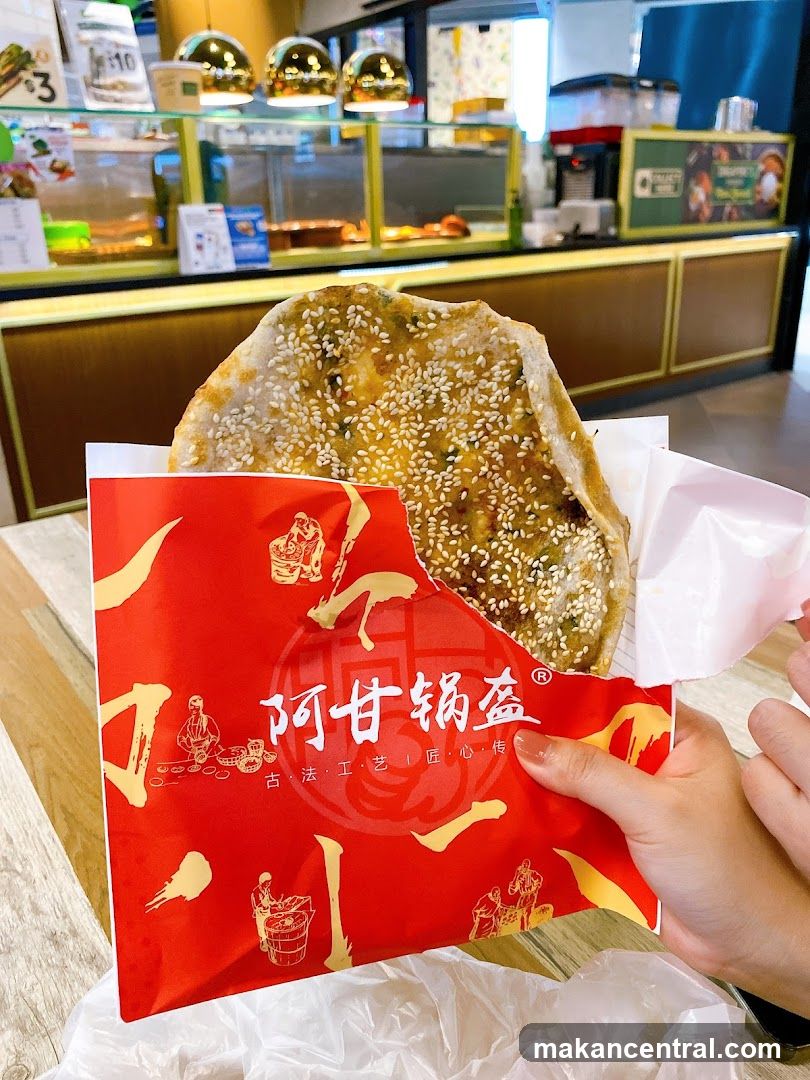 Hand holding food item with branded paper wrapper
