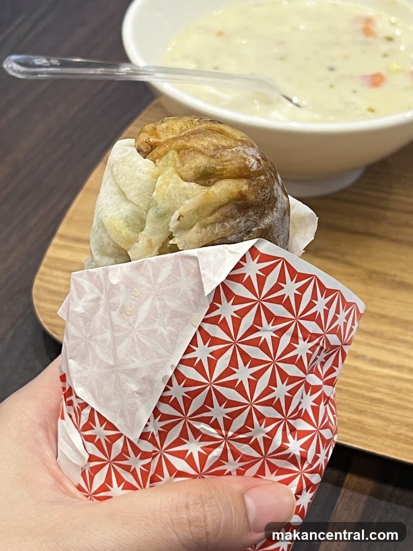 Hand holding food item with soup in background