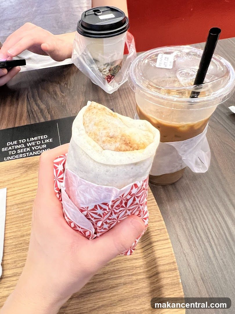 Hand holding food item with drinks on table