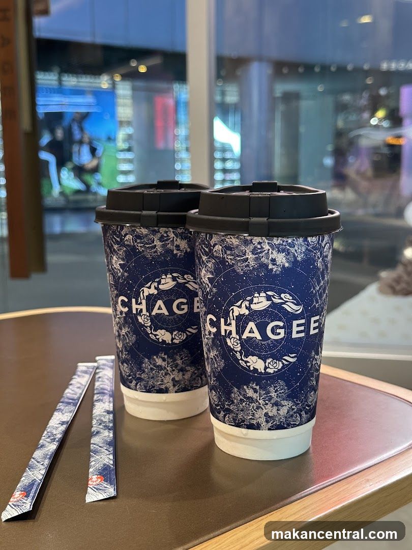 Two takeaway coffee cups with lids and two sugar packets on a table