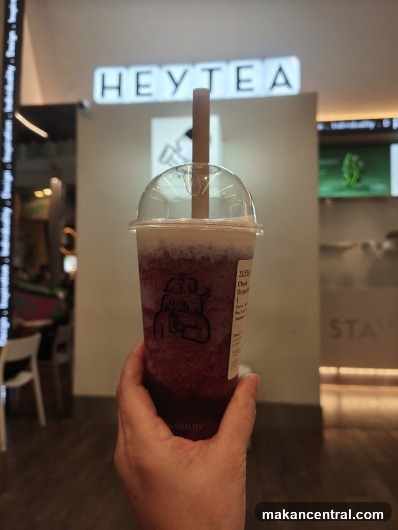 Person holding a purple drink in front of a HEYTEA storefront