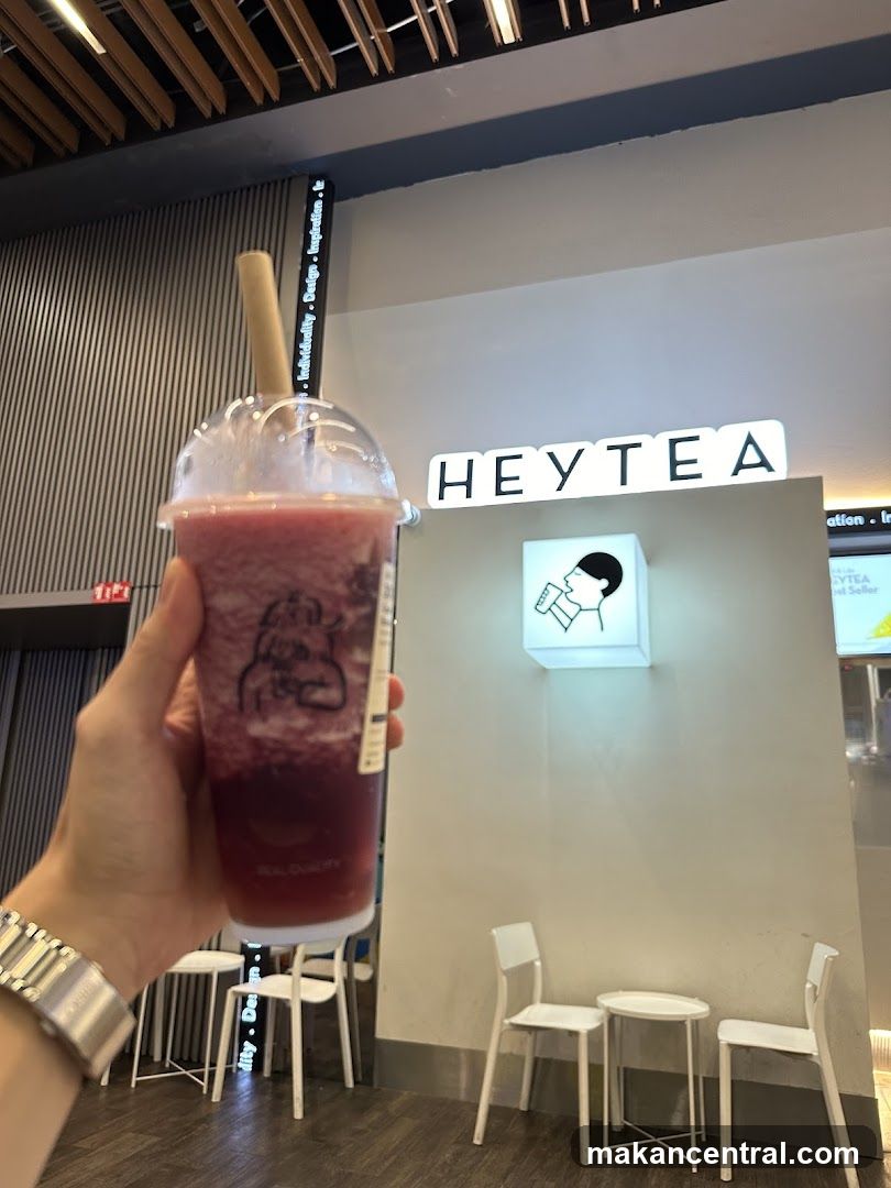 Person holding a beverage in front of a HEYTEA store