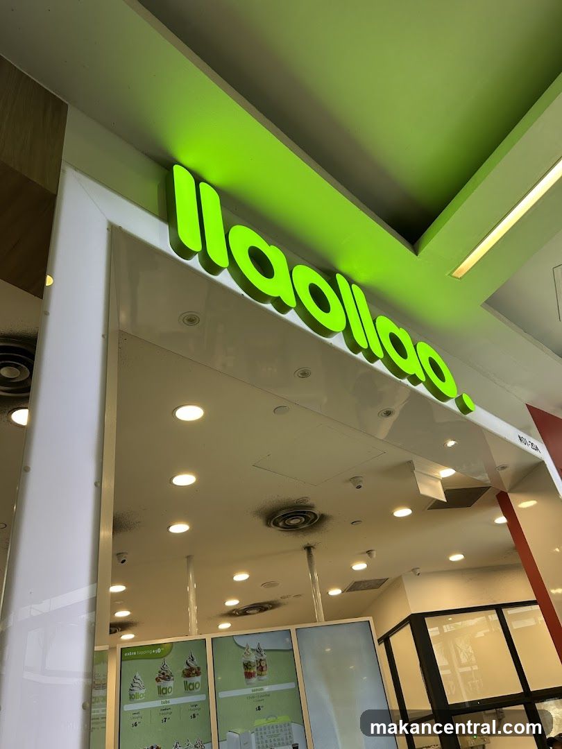 A bright green Llaollao sign is visible above the entrance of a store. Below the sign, a menu board displays images of frozen yogurt and smoothies with prices.