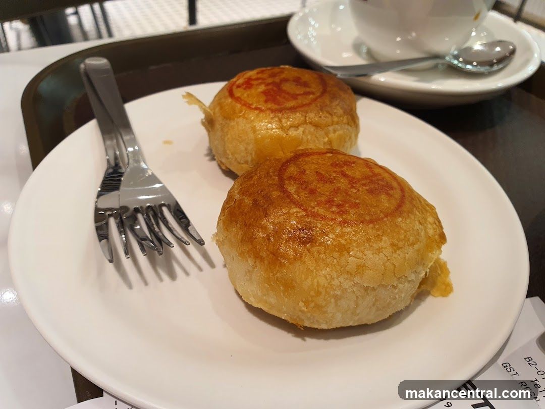 Two pastries on a plate with forks and a cup of tea