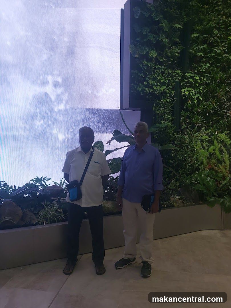 Two Men Posing in Front of a Digital Waterfall and Green Wall