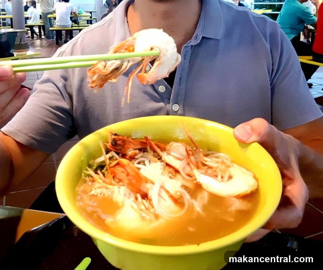 Person eating prawn noodle soup