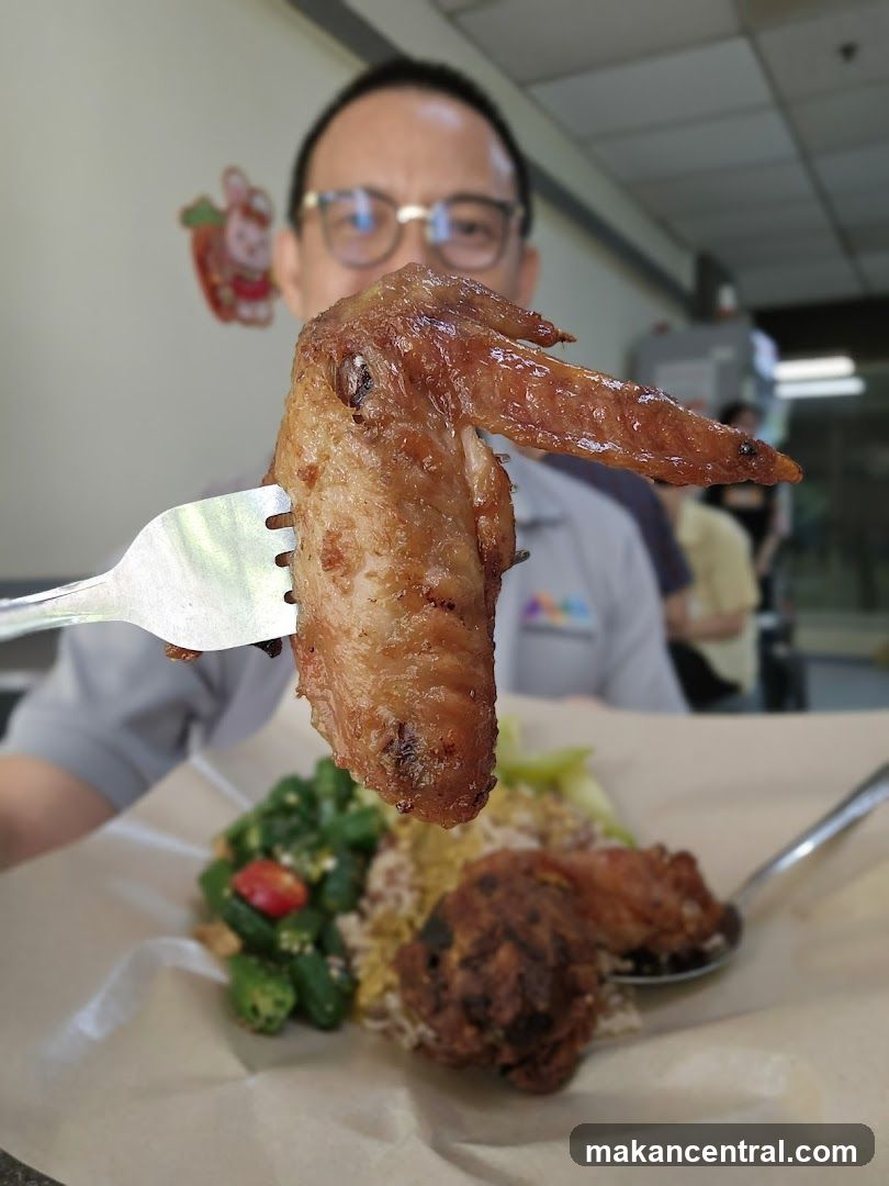 Person holding a chicken wing over a plate of food