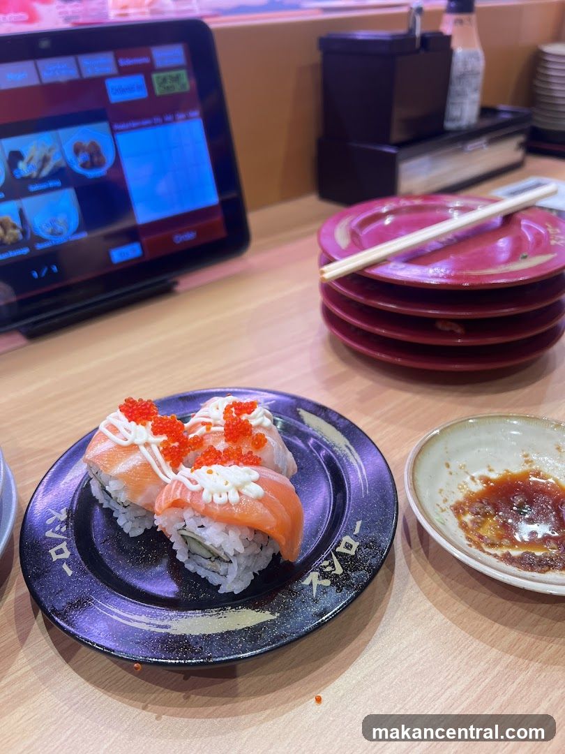 Sushi on a plate with a tablet and stacked plates