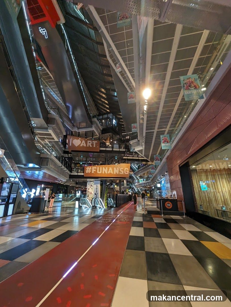 Indoor mall walkway with escalators and signage