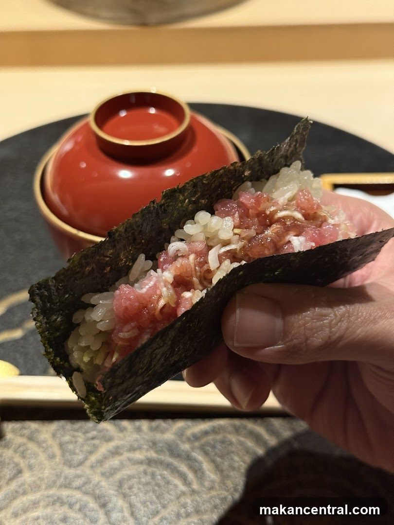 Hand holding a tuna and rice hand roll