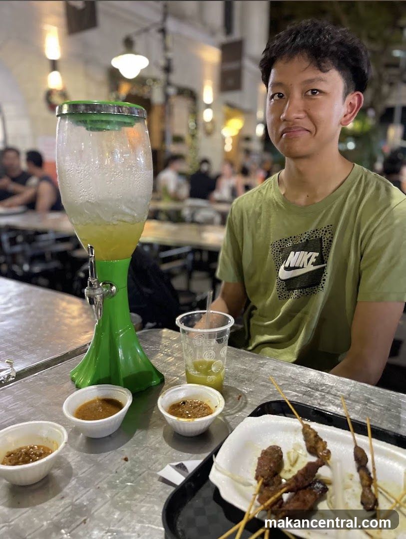 Man with drinks and satay