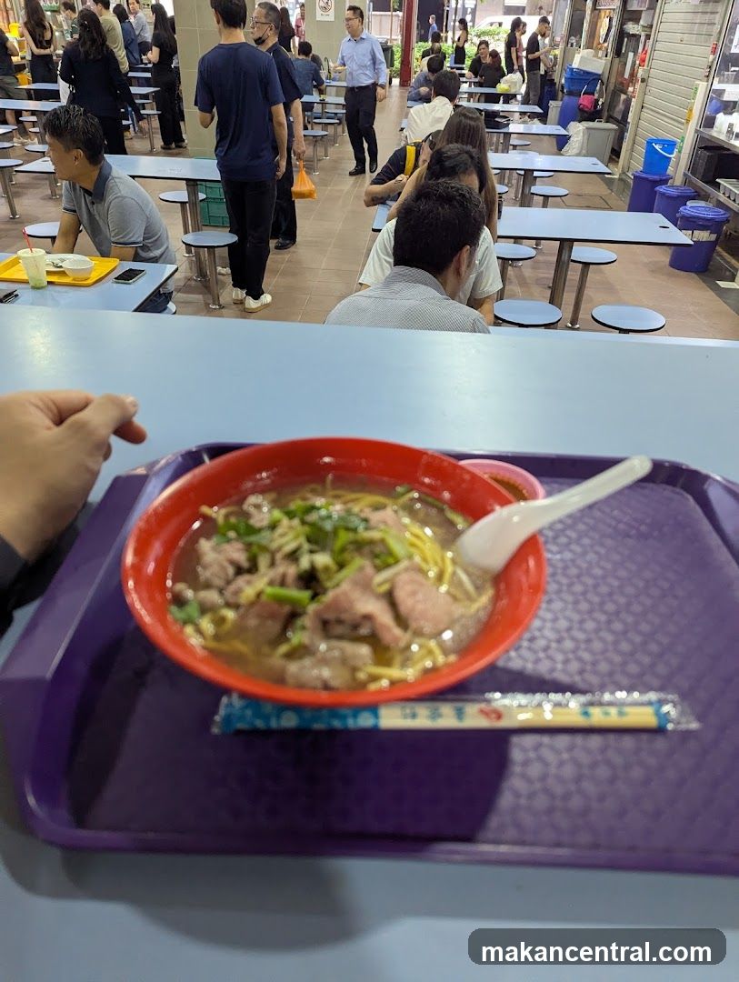 Food court with diners and a bowl of noodles