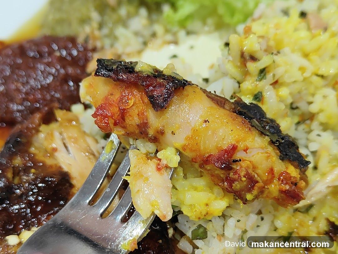 Close-up of a fork lifting a piece of grilled fish with rice