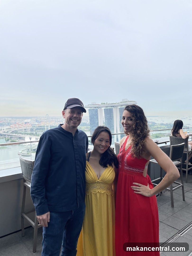 Three people posing for a photo with a city view