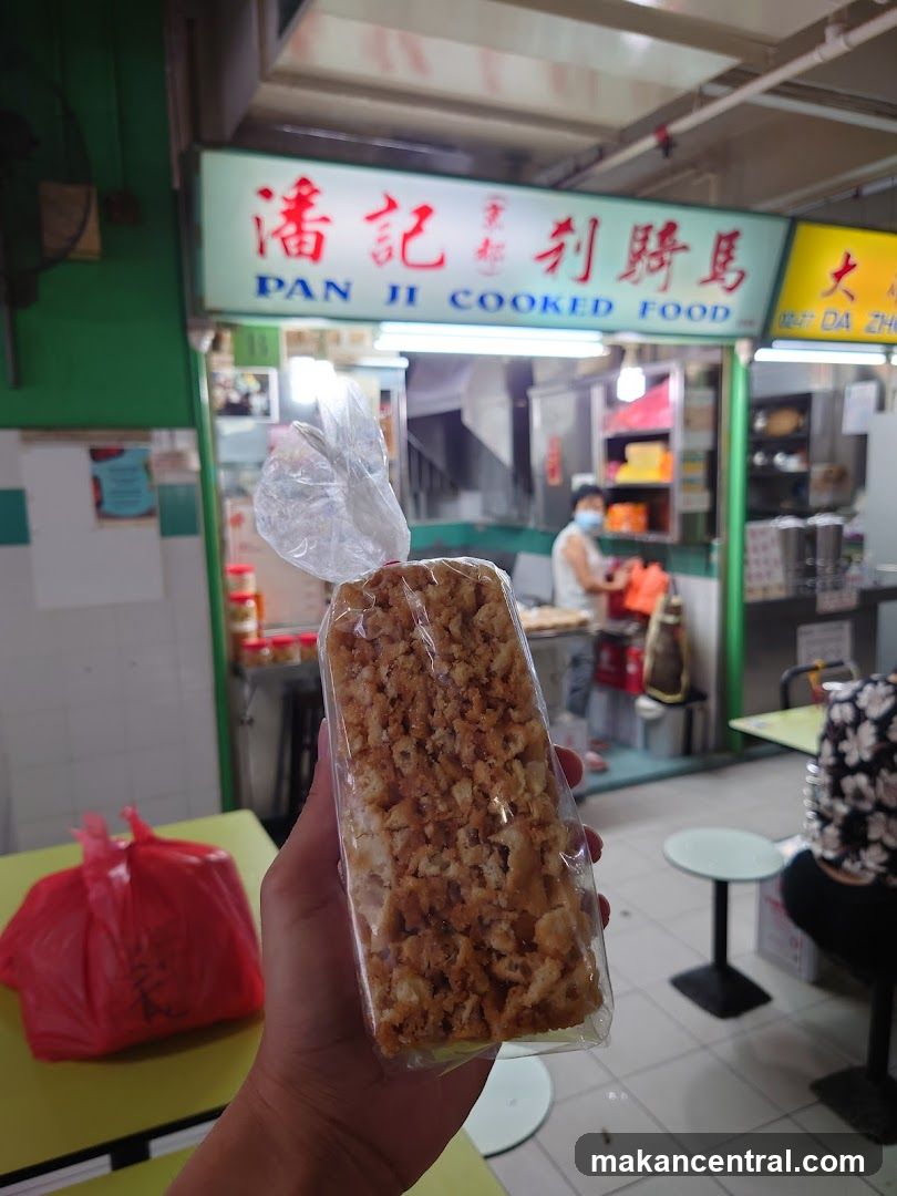 Person holding a packaged food item in front of a food stall