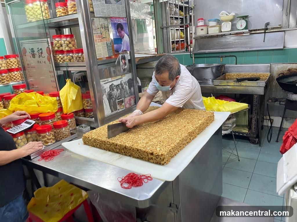 Man cutting a large block of peanut brittle