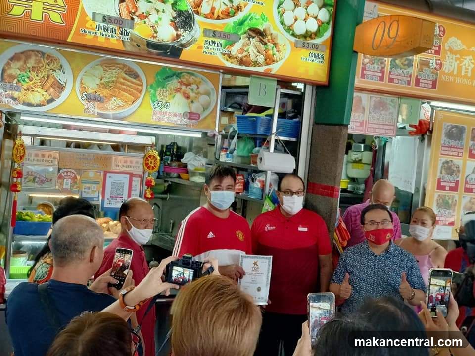 People posing for photos in front of a food stall