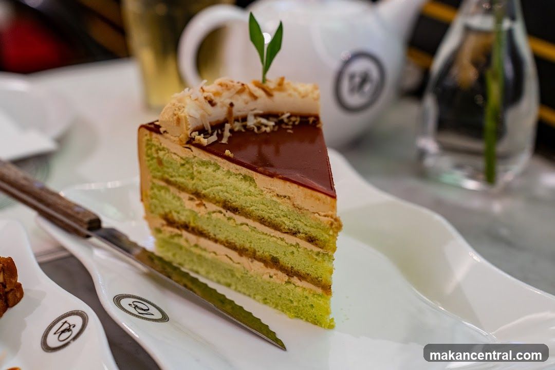 Slice of layered green cake with chocolate glaze